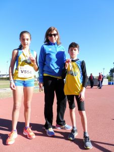 Els medallistes alevins del CA Safor, Julia Estruch i Xavi Cabanilles, amb la seua entrenadora, Montse Climent.